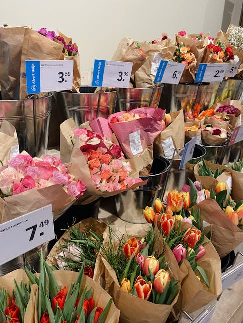 A display of various floral bouquets arranged in metal buckets and delivered in brown craft paper, showcasing a range of fresh flowers including pink roses, orange and pink tulips, and mixed blossoms 